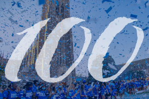 Duke 100 Celebration image with students in background with blue and white confetti raining down. Number 100 in front of image in white lettering againgst blue tinted image.