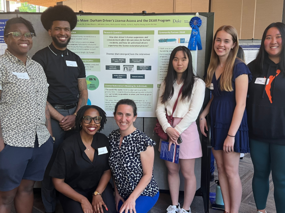 Photo of various students from Bass Connections standing together in front of research poster