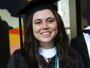 Portrait photo of sociology student Julia Murrow wearing graduation cap and gown and multiple honor cords.
