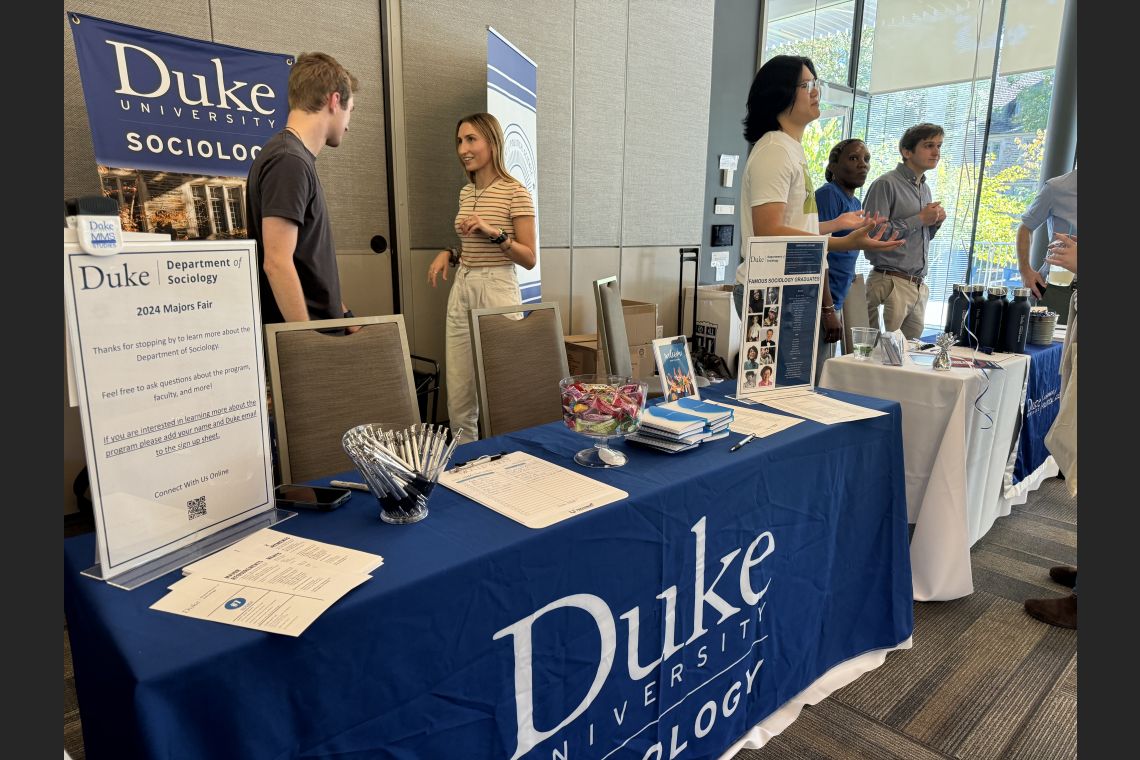 Photo of Duke Sociology table with two student ambassadors in conversation behind the table